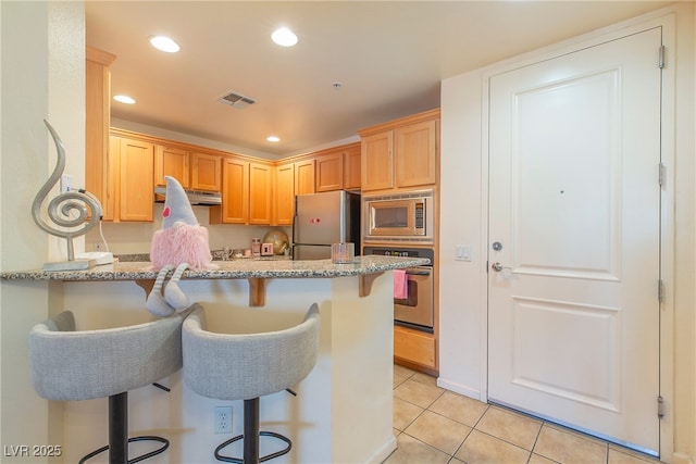 kitchen featuring light stone countertops, a kitchen breakfast bar, kitchen peninsula, and appliances with stainless steel finishes