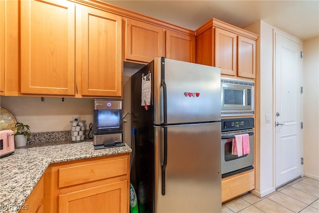 kitchen with light stone countertops, appliances with stainless steel finishes, and light tile patterned floors