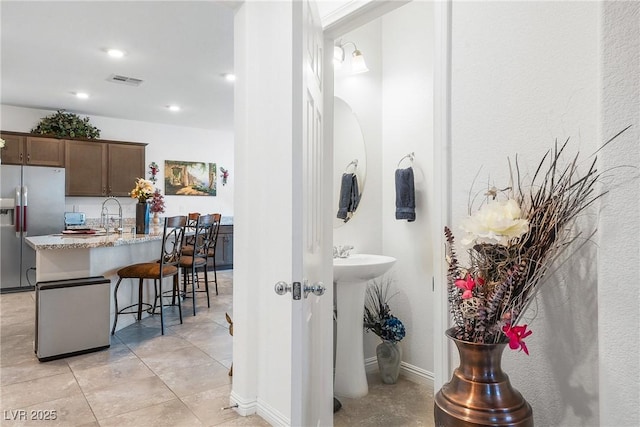 bathroom with baseboards, visible vents, tile patterned floors, a sink, and recessed lighting