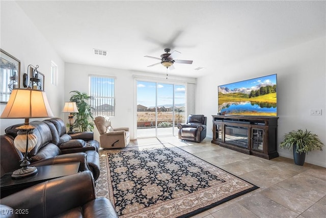 living area with ceiling fan, visible vents, baseboards, and a glass covered fireplace