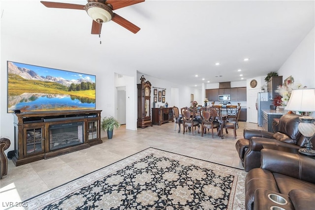 living room featuring light tile patterned flooring, a glass covered fireplace, a ceiling fan, and recessed lighting