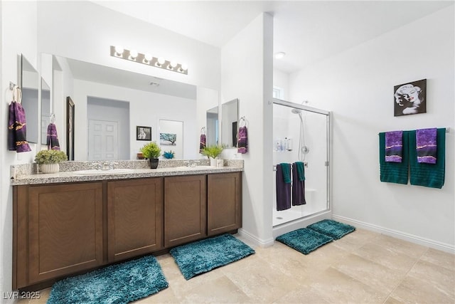 bathroom with a stall shower, a sink, baseboards, and double vanity