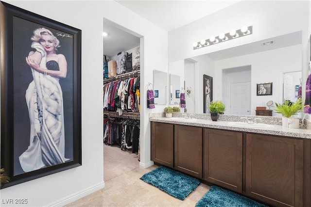 bathroom with visible vents, a sink, a spacious closet, and double vanity