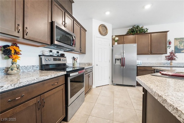 kitchen featuring stainless steel appliances, light tile patterned flooring, dark brown cabinetry, and recessed lighting