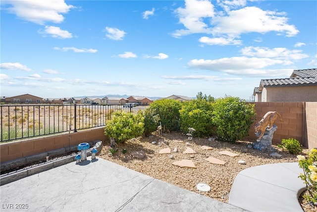 view of yard featuring a fenced backyard, a residential view, and a patio