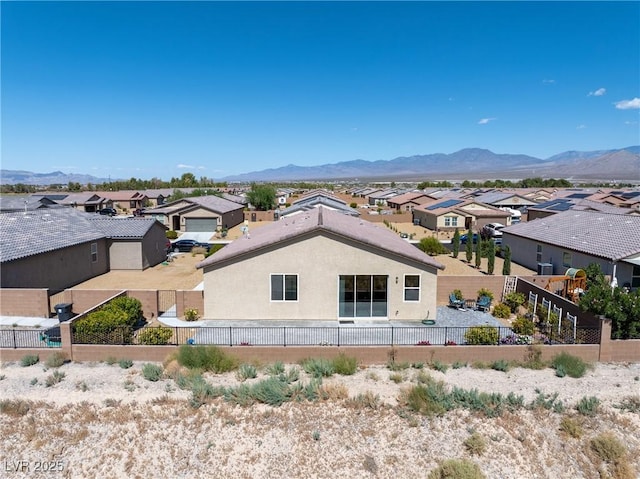 rear view of property featuring a residential view, a fenced backyard, a mountain view, and stucco siding