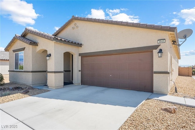 view of front of home featuring driveway, an attached garage, a tile roof, and stucco siding