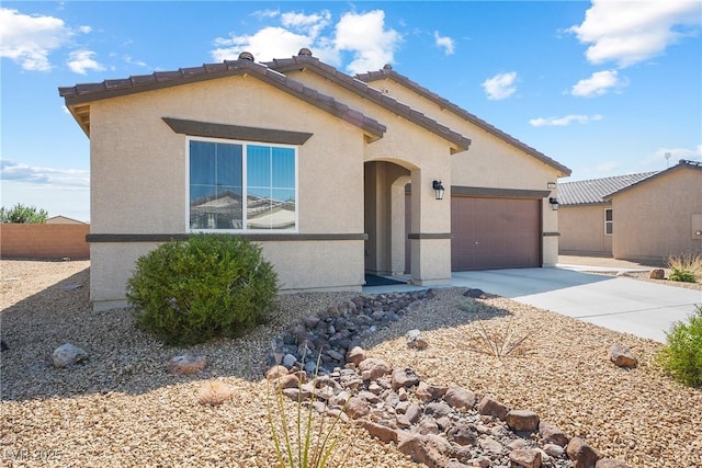 view of front of house featuring a garage, a tiled roof, concrete driveway, and stucco siding