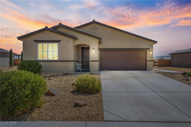 view of front facade featuring driveway, an attached garage, a tile roof, and stucco siding