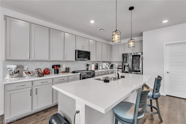 4267 E Highvale Ct, Pahrump, NV 89061 - kitchen with light wood-type flooring, a kitchen bar, decorative backsplash, and appliances with stainless steel finishes