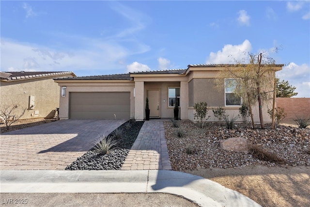 view of front of property with decorative driveway, a garage, a tile roof, and stucco siding