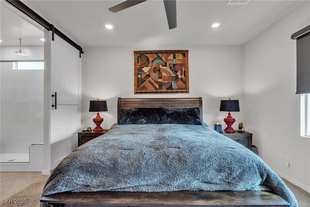 bedroom with ceiling fan, connected bathroom, a barn door, and tile patterned floors