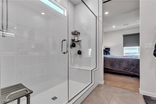 bathroom with plenty of natural light, a shower with shower door, and tile patterned flooring