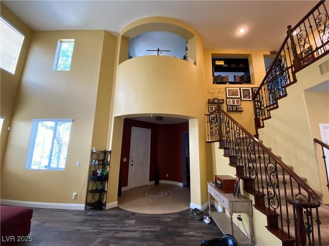 entryway with a towering ceiling and dark hardwood / wood-style floors