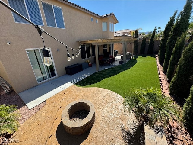 rear view of property featuring a fire pit, a yard, a pergola, and a patio