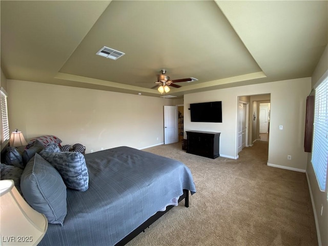 bedroom with ceiling fan, carpet flooring, and a tray ceiling