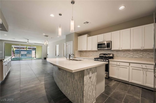 kitchen with appliances with stainless steel finishes, sink, a center island with sink, and white cabinets