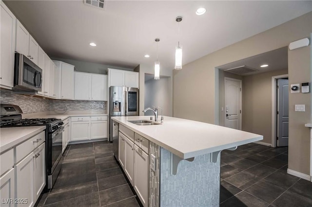 kitchen with pendant lighting, white cabinetry, sink, stainless steel appliances, and a center island with sink