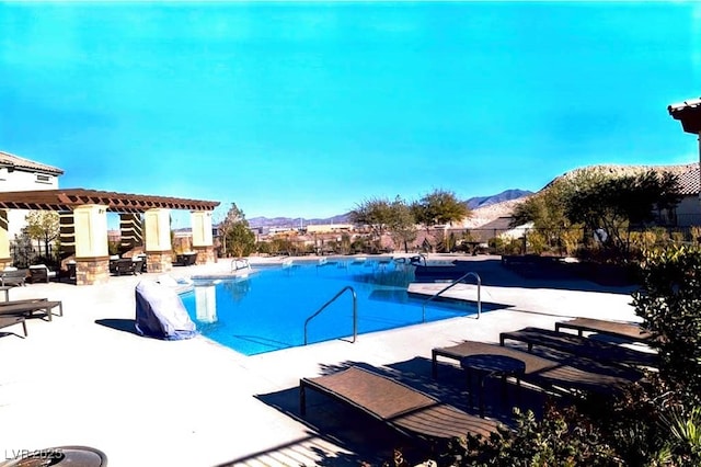 community pool featuring a mountain view, a patio, and a pergola