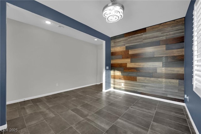 unfurnished room with dark tile patterned flooring, recessed lighting, wood walls, baseboards, and an accent wall