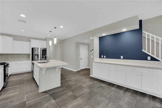 kitchen featuring visible vents, a sink, decorative backsplash, light countertops, and appliances with stainless steel finishes