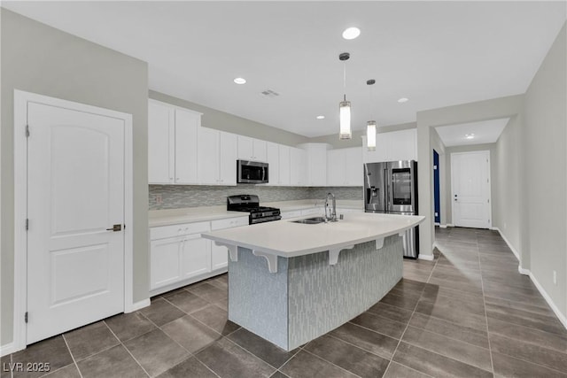 kitchen with dark tile patterned flooring, decorative backsplash, stainless steel appliances, and a sink