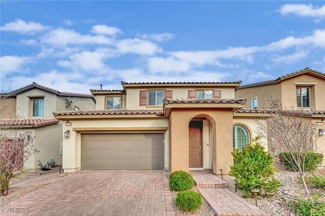 mediterranean / spanish-style house featuring stucco siding, decorative driveway, and a tiled roof