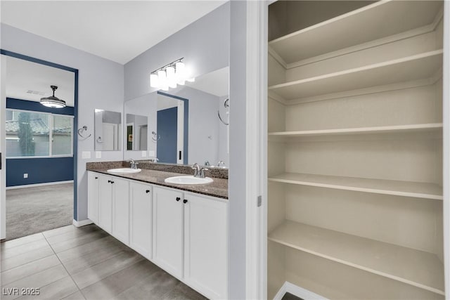 bathroom with a sink, baseboards, and double vanity