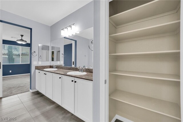 bathroom with baseboards, a sink, tile patterned flooring, and double vanity