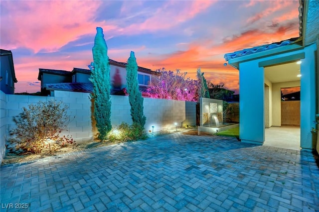 patio terrace at dusk featuring a fenced backyard