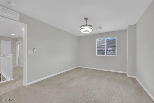 unfurnished room featuring baseboards, visible vents, and light carpet