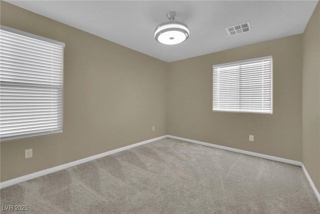 carpeted empty room with baseboards, visible vents, and plenty of natural light