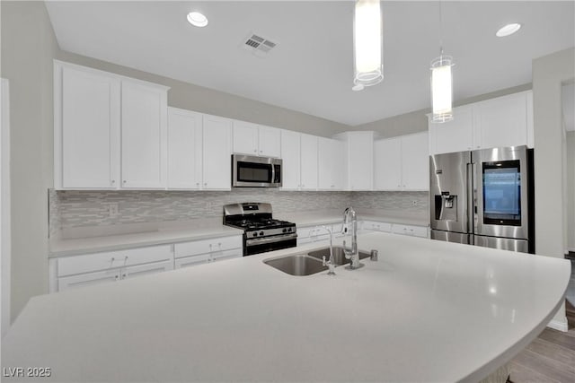 kitchen with white cabinets, a sink, visible vents, backsplash, and appliances with stainless steel finishes