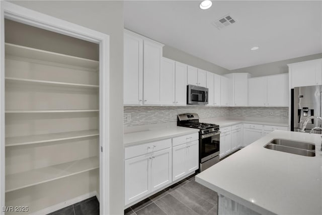 kitchen with a sink, visible vents, decorative backsplash, light countertops, and appliances with stainless steel finishes