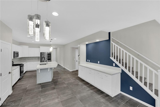 kitchen with a center island with sink, black gas range oven, stainless steel refrigerator with ice dispenser, light countertops, and hanging light fixtures