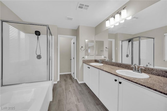 bathroom with a sink, visible vents, wood finished floors, and a shower stall