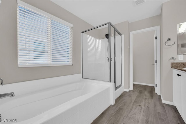 bathroom featuring visible vents, a stall shower, wood finished floors, a bath, and vanity