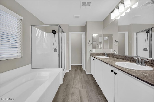 bathroom with a shower stall, wood finished floors, a sink, and visible vents