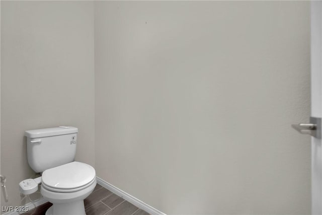 bathroom featuring toilet, baseboards, and wood tiled floor