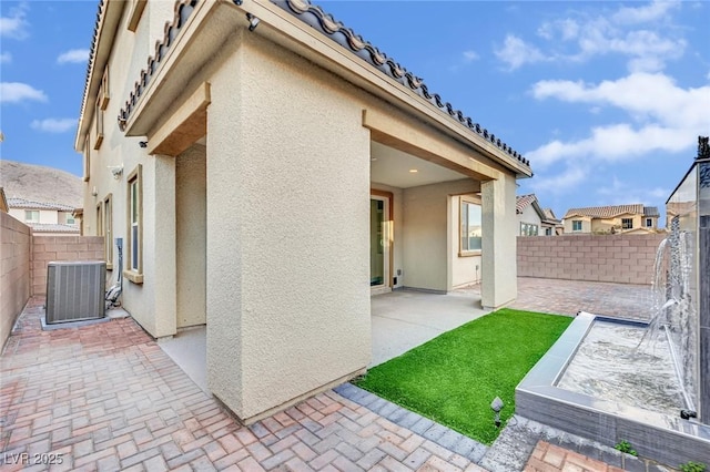 back of property featuring a tiled roof, central AC unit, stucco siding, a fenced backyard, and a patio