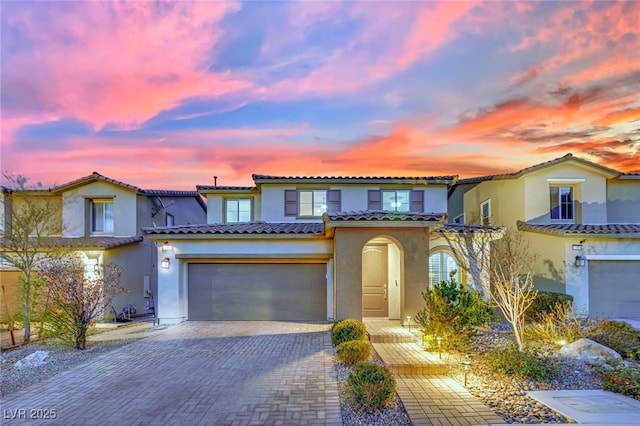mediterranean / spanish home with stucco siding, a tile roof, and decorative driveway