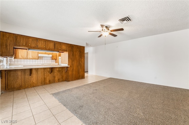 unfurnished living room featuring light tile patterned flooring, sink, a textured ceiling, and ceiling fan