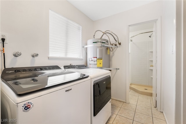 laundry area featuring light tile patterned flooring, washer and dryer, and strapped water heater