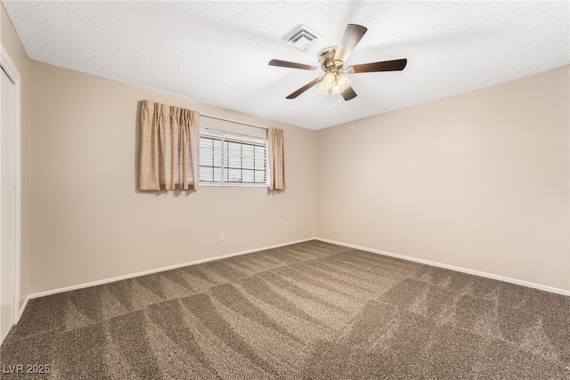 spare room with dark colored carpet, ceiling fan, and a textured ceiling