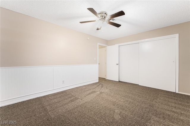 unfurnished bedroom featuring ceiling fan, a closet, carpet floors, and a textured ceiling