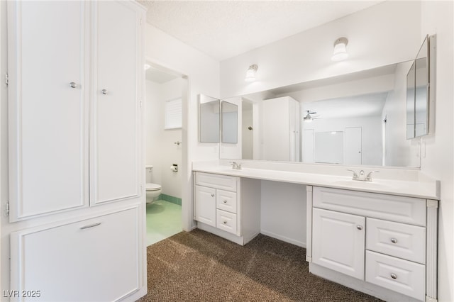 bathroom with vanity, toilet, and a textured ceiling