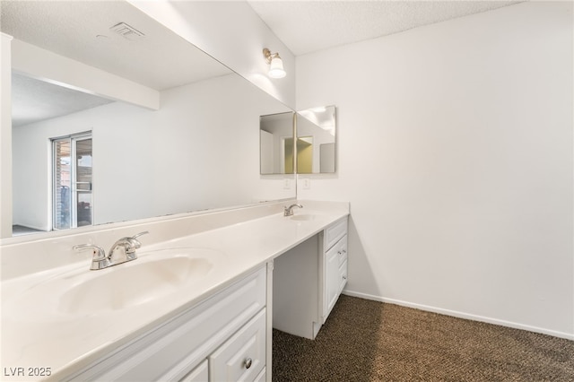 bathroom with beamed ceiling, vanity, and a textured ceiling