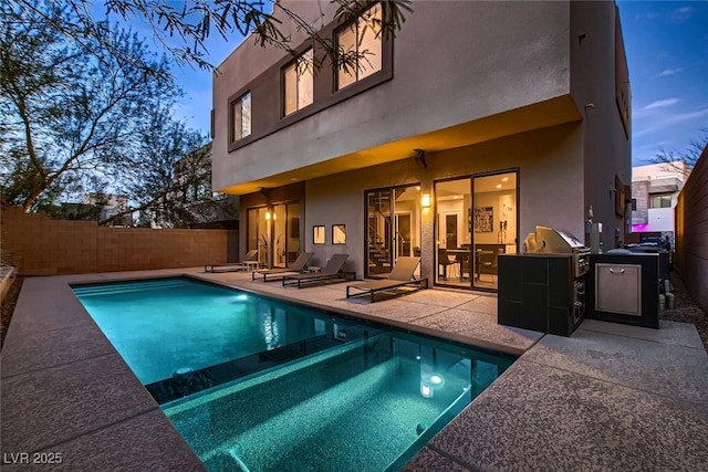 back house at dusk featuring a fenced in pool and a patio area