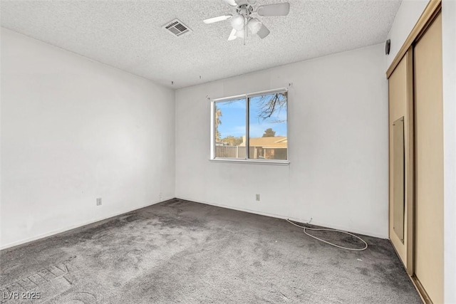 unfurnished bedroom with dark colored carpet, ceiling fan, a textured ceiling, and a closet