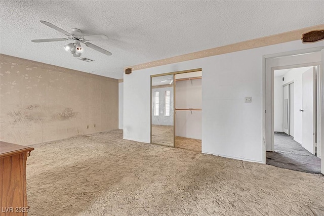 carpeted empty room with ceiling fan and a textured ceiling